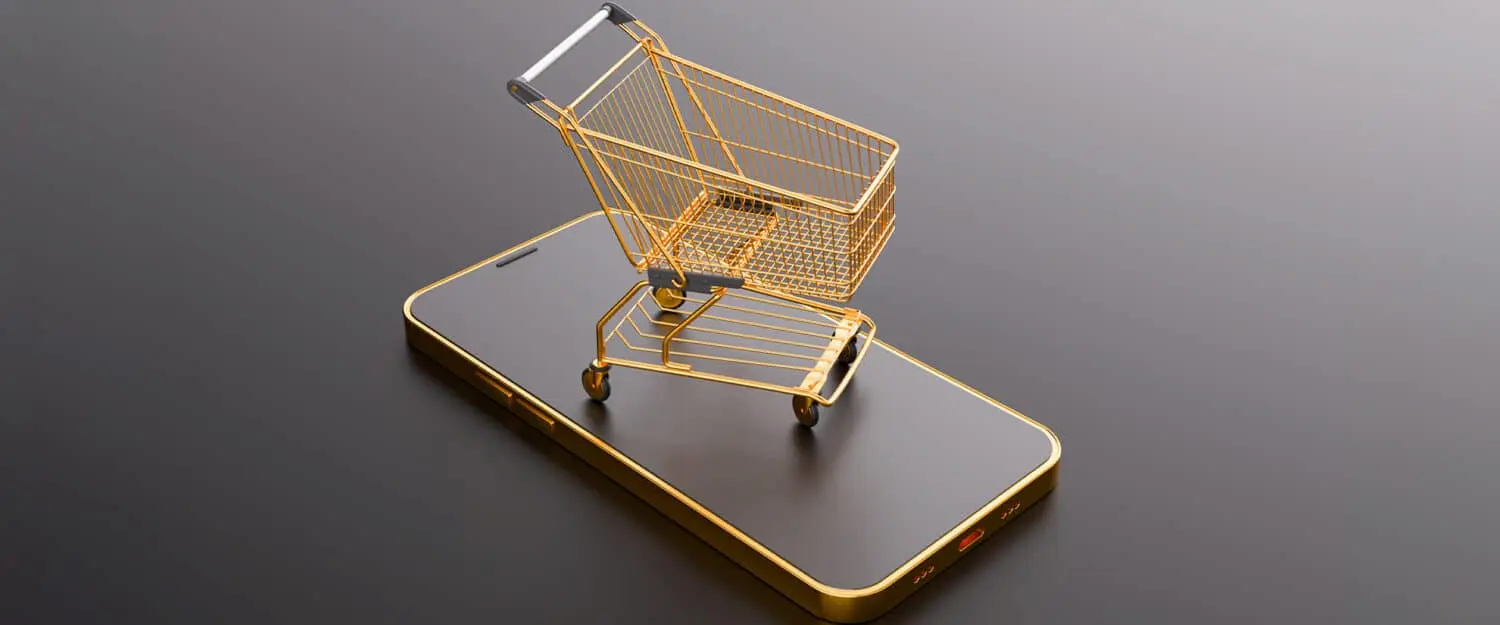 Concetto di shopping online con un carrello dorato posizionato sopra uno smartphone, simbolo del commercio digitale