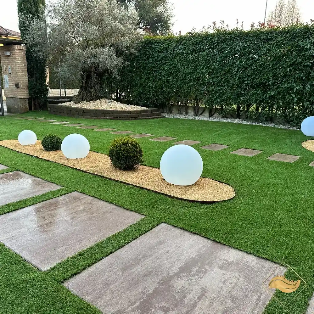 Giardino moderno con erba sintetica, pavimentazione carrabile e lampade sferiche di design per illuminazione elegante